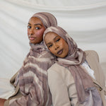 Two women wearing brown sediment printed hijabs against a white background