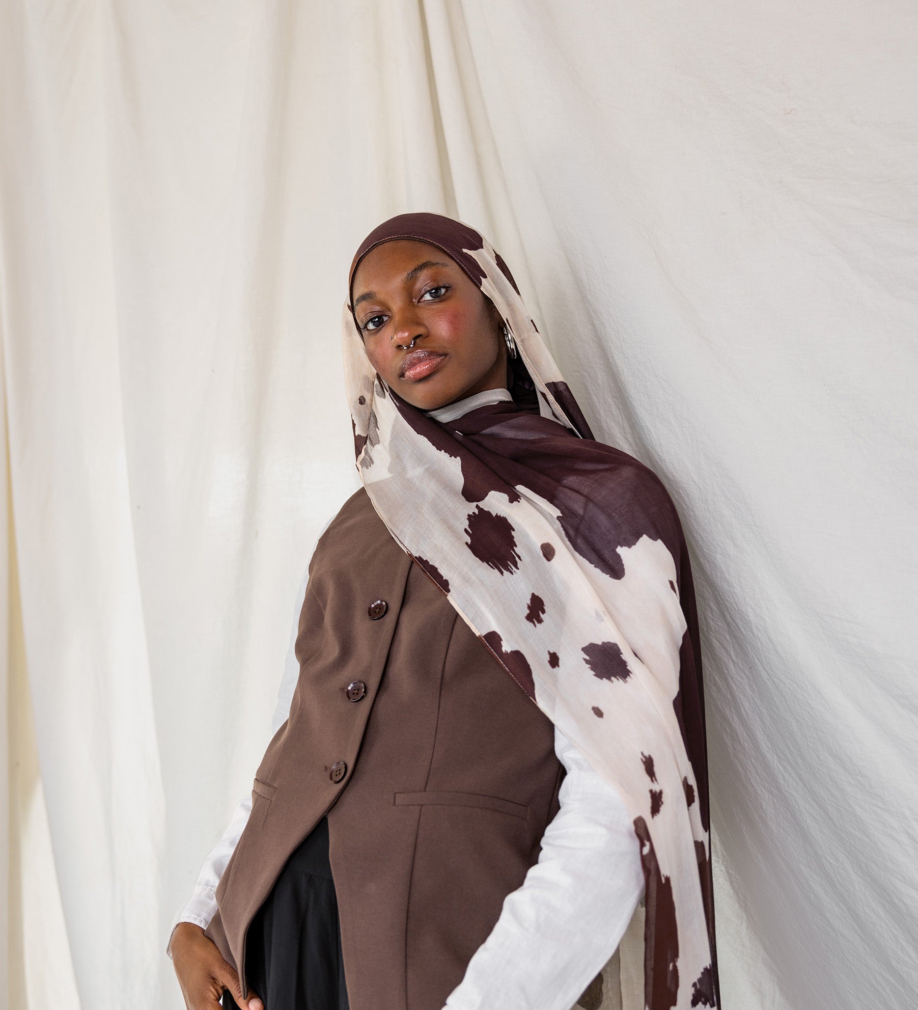 Model shown posing in Prairie Hide, a cream scarf with chocolate brown splotches.