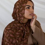 A woman wearing a brown red toned paisley print hijab.