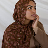 A woman wearing a brown red toned paisley print hijab.