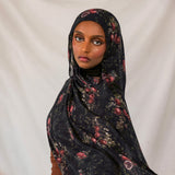 Woman wearing a dark pomegranate hijab against a plain background