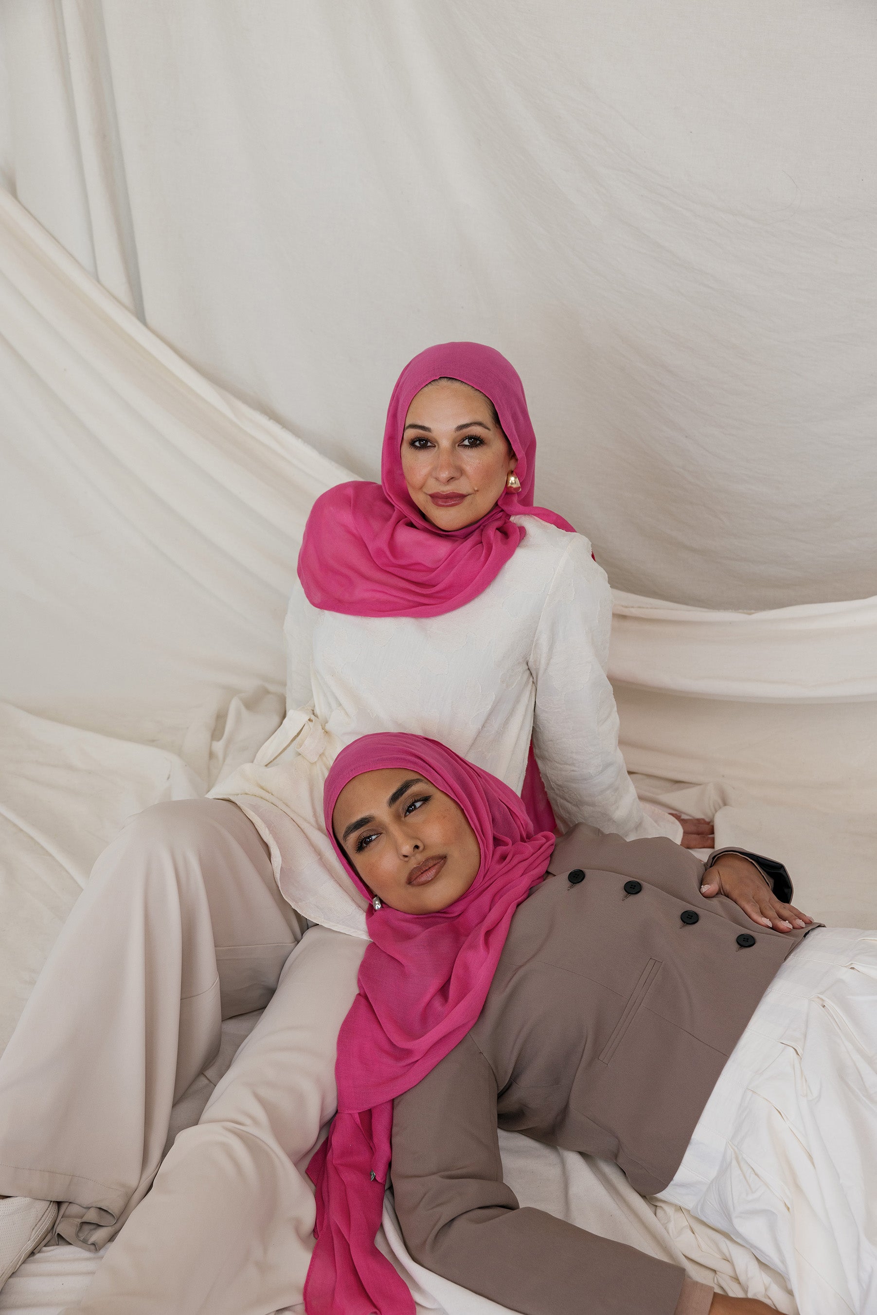 Two models shown posed in Rose Wave, a wearable version of a hot pink toned scarf.