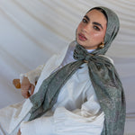 A model styled in a green toned paisley printed hijab with a hijab hoop.