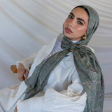 A model styled in a green toned paisley printed hijab with a hijab hoop.