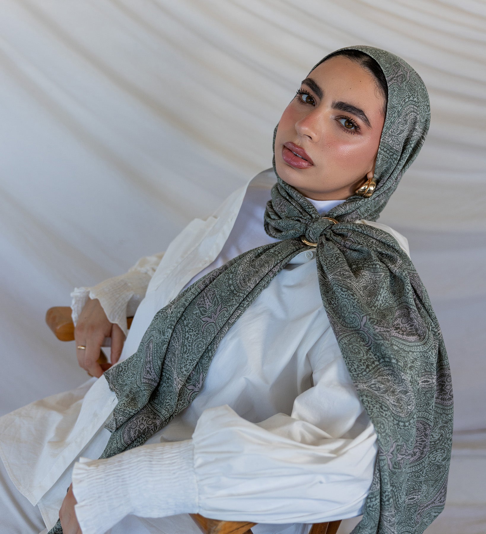 A model styled in a green toned paisley printed hijab with a hijab hoop.