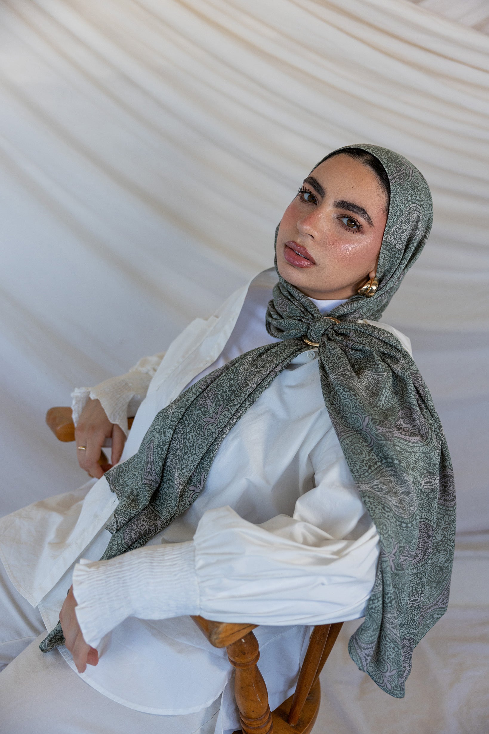 A model styled in a green toned paisley printed hijab with a hijab hoop.