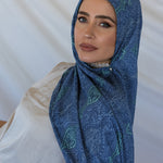 A woman modeling a blue toned paisley print hijab using a hijab magnet.