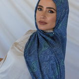 A woman modeling a blue toned paisley print hijab using a hijab magnet.