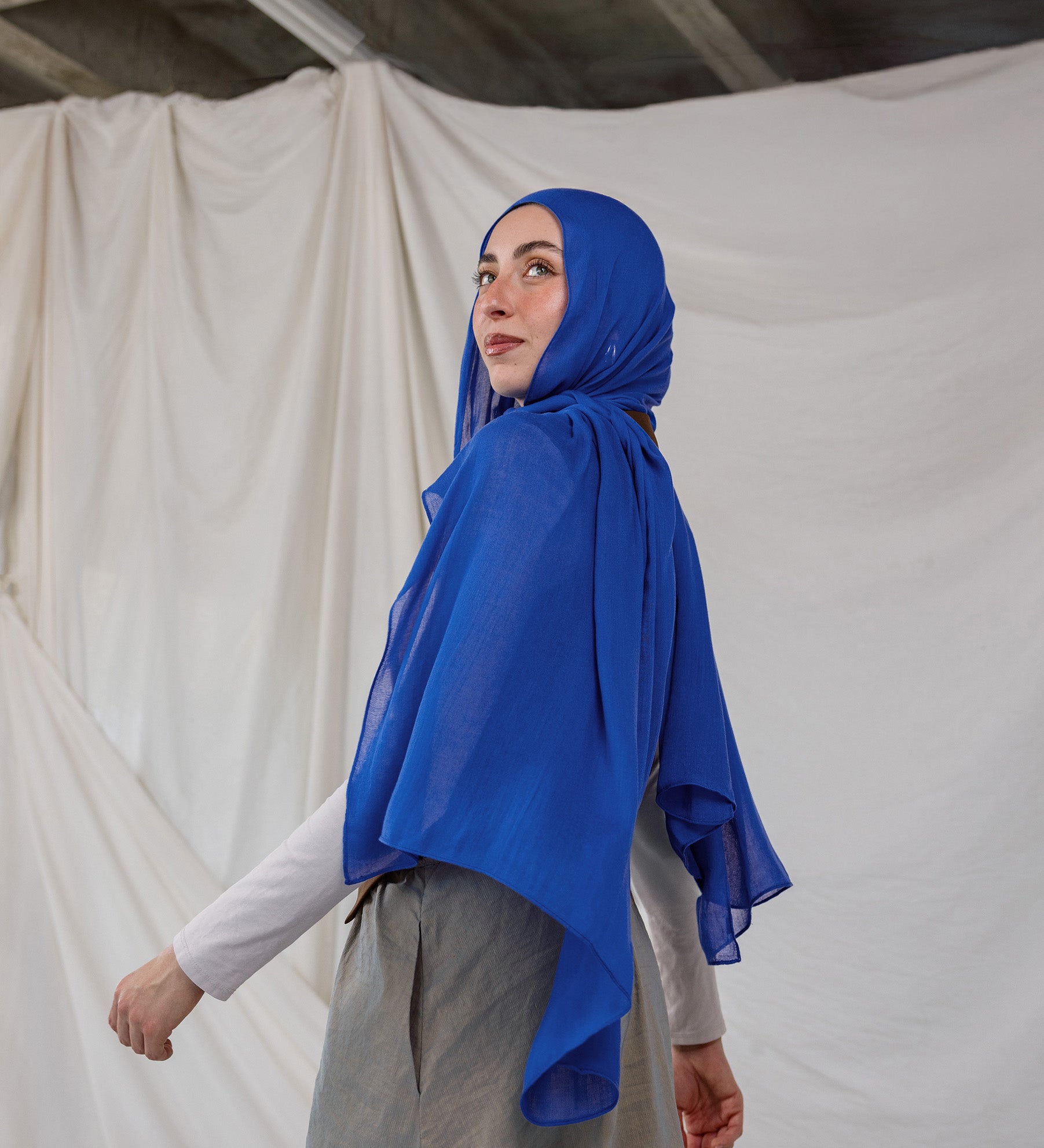Spirulina Blue scarf pictured on model, this scarf by VELA is bright electric blue.