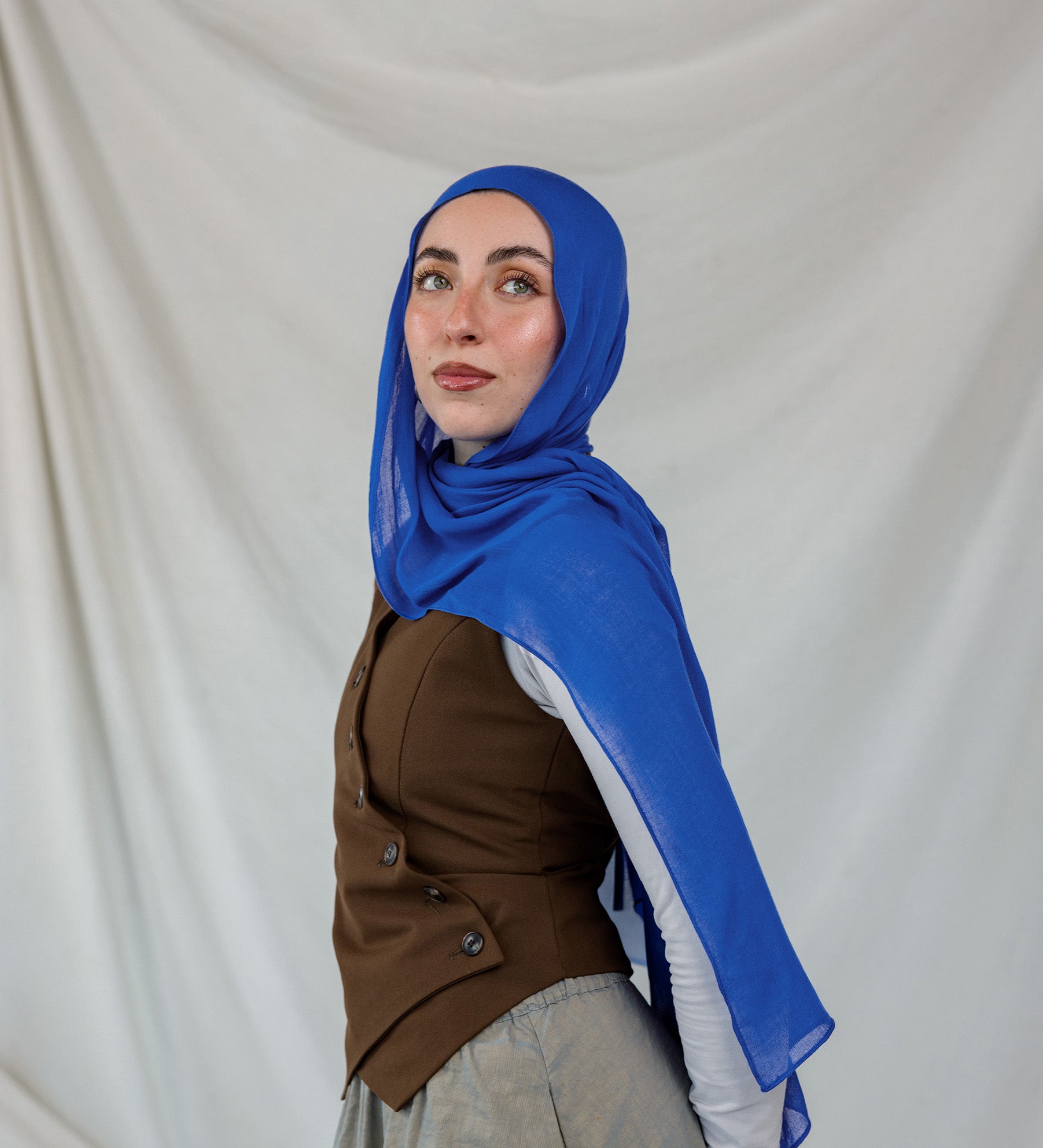 Model shown posing in Spirulina Blue, a vivid, electric Blue scarf by VELA.