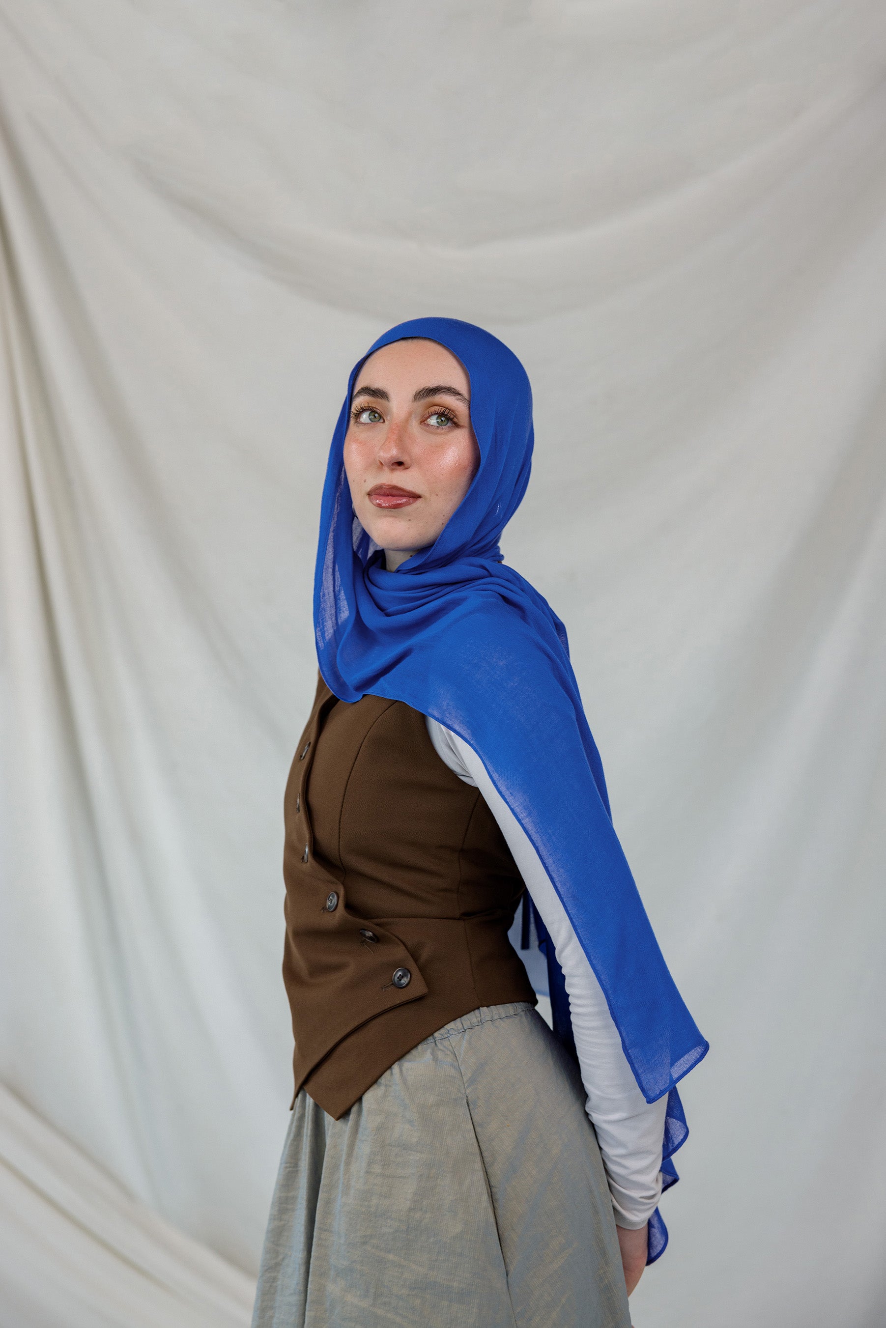 Model shown posing in Spirulina Blue, a vivid, electric Blue scarf by VELA.