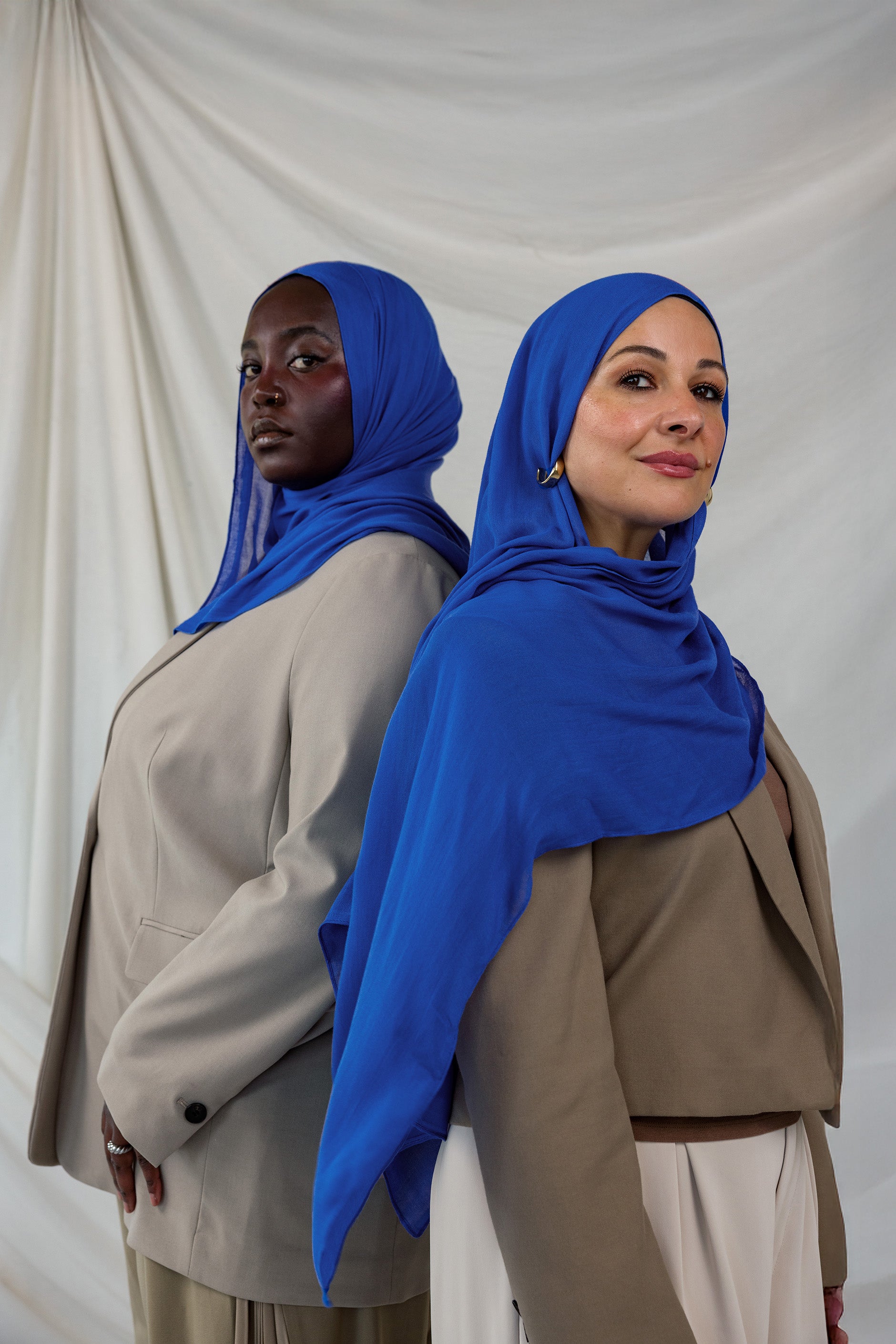 Two models shown posing together wearing Spirulina Blue, a vivid electric blue toned scarf by VELA.