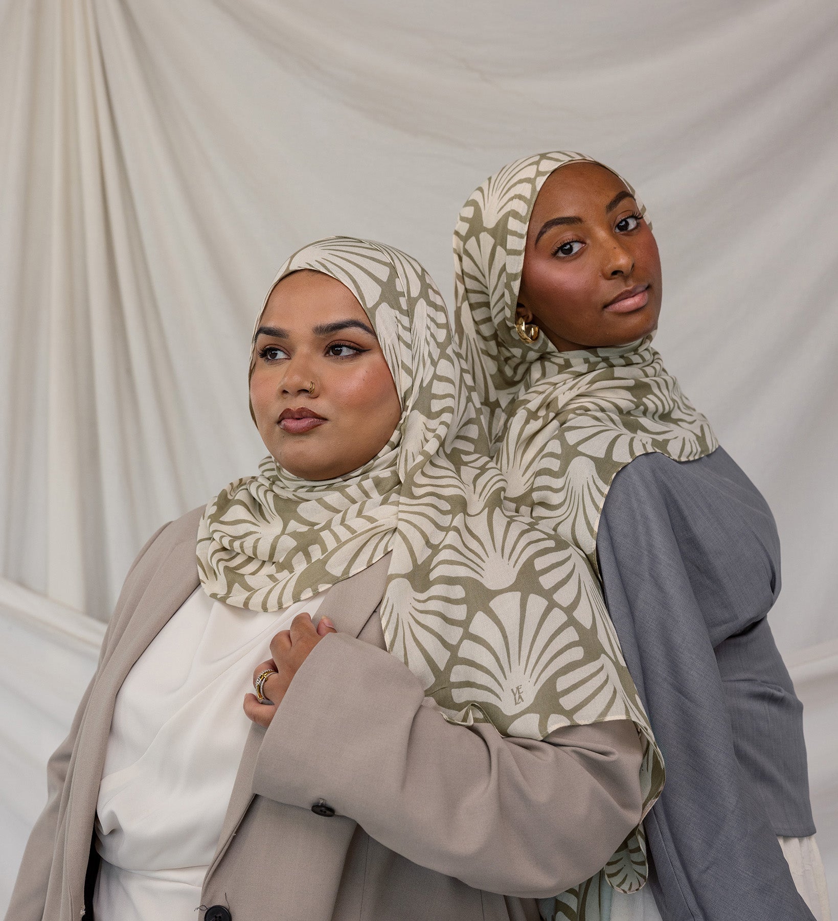 Two women side by side in matching beige and white leaf print hijabs, styled against white background.