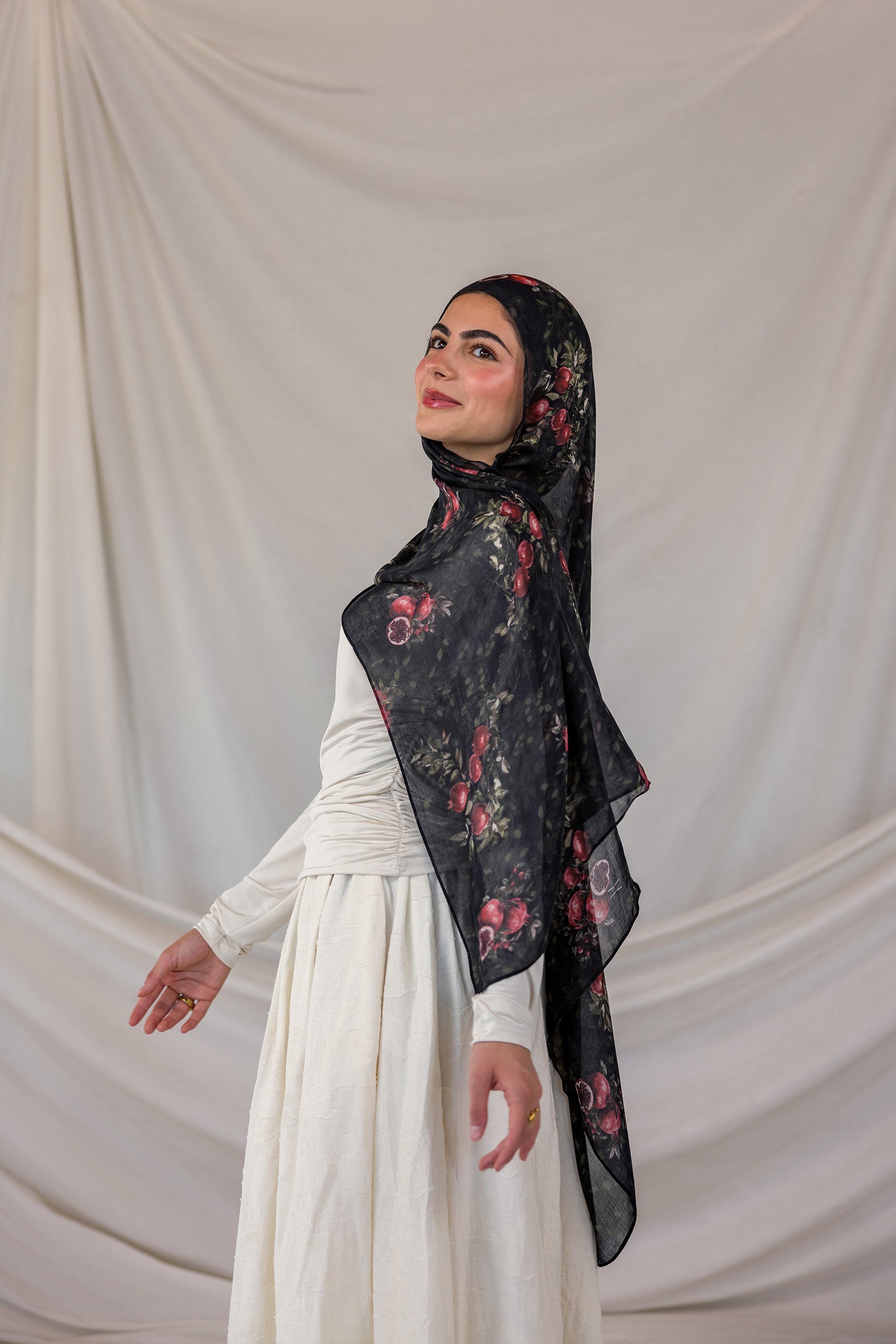 Woman wearing a black pomegranate hijab against a plain background