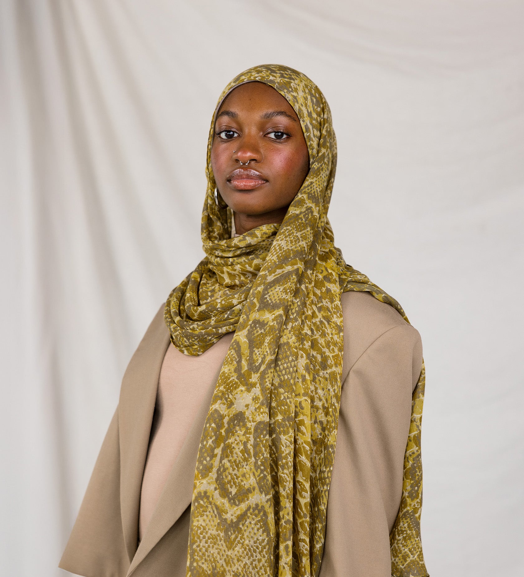 Model posing in Golden Cobra, a golden/yellow snakeskin print scarf.