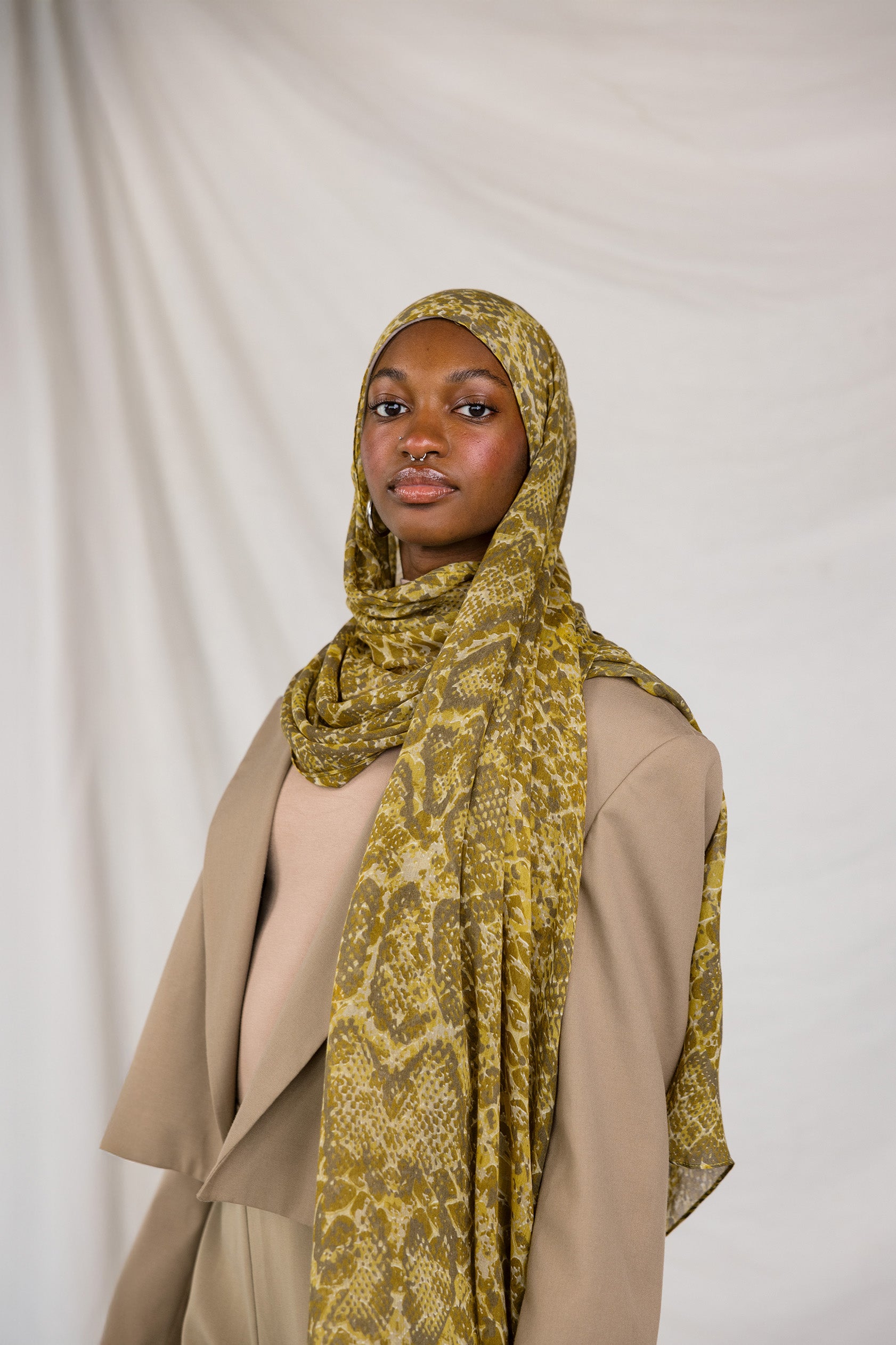 Model posing in Golden Cobra, a golden/yellow snakeskin print scarf.