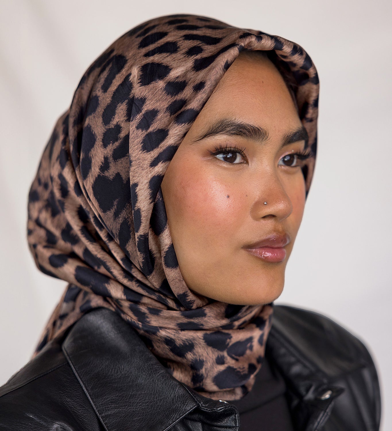 A woman wearing a leopard printed silk hijab.