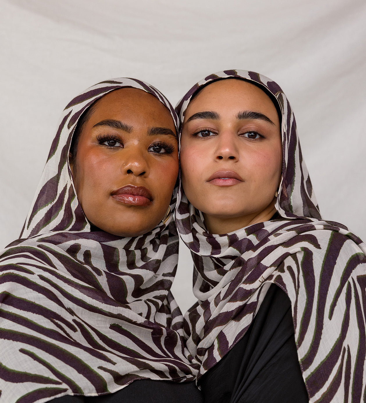 Two models shown wearing VELA's Zebra print, which features a white base and deep berry-toned stripes throughout.