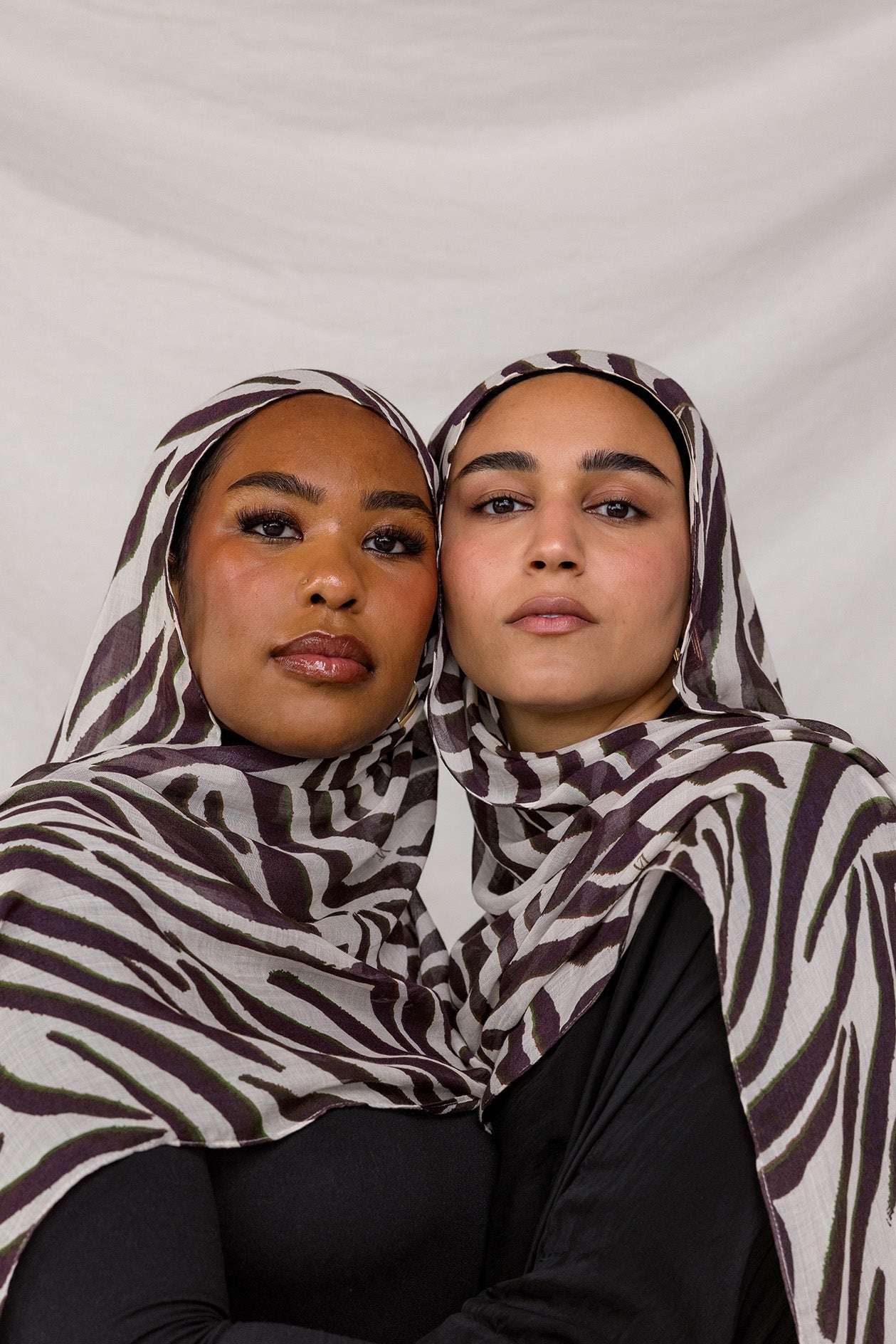Two models shown wearing VELA's Zebra print, which features a white base and deep berry-toned stripes throughout.