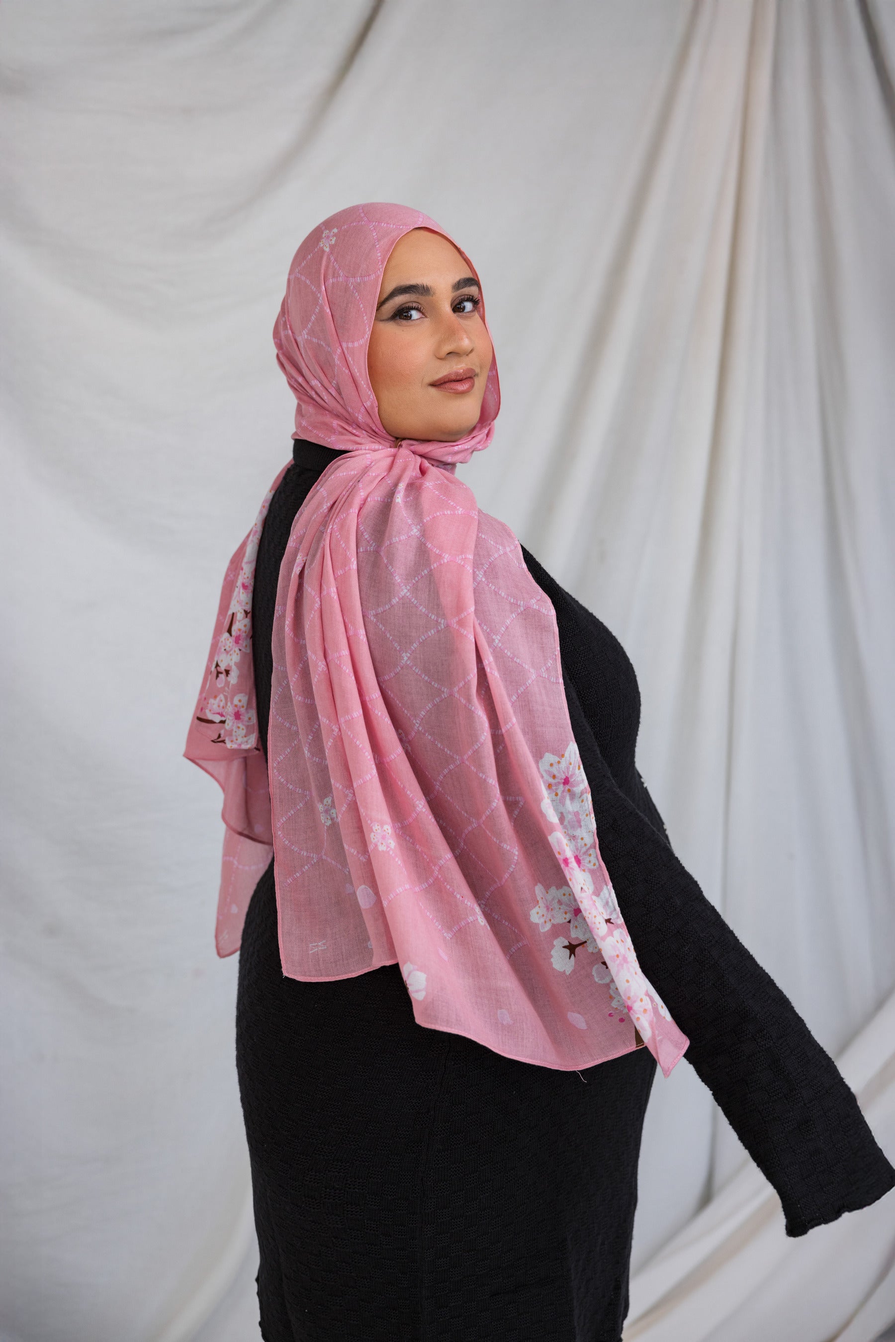 Model styled in a pink printed hijab featuring sakura pink and white cherry blossoms.