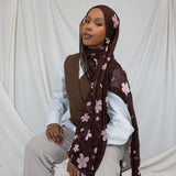 A woman wearing a brown hijab printed with pink and white cherry blossoms.