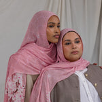 Two models styled in a pink printed hijab featuring cherry blossoms in pink and white.