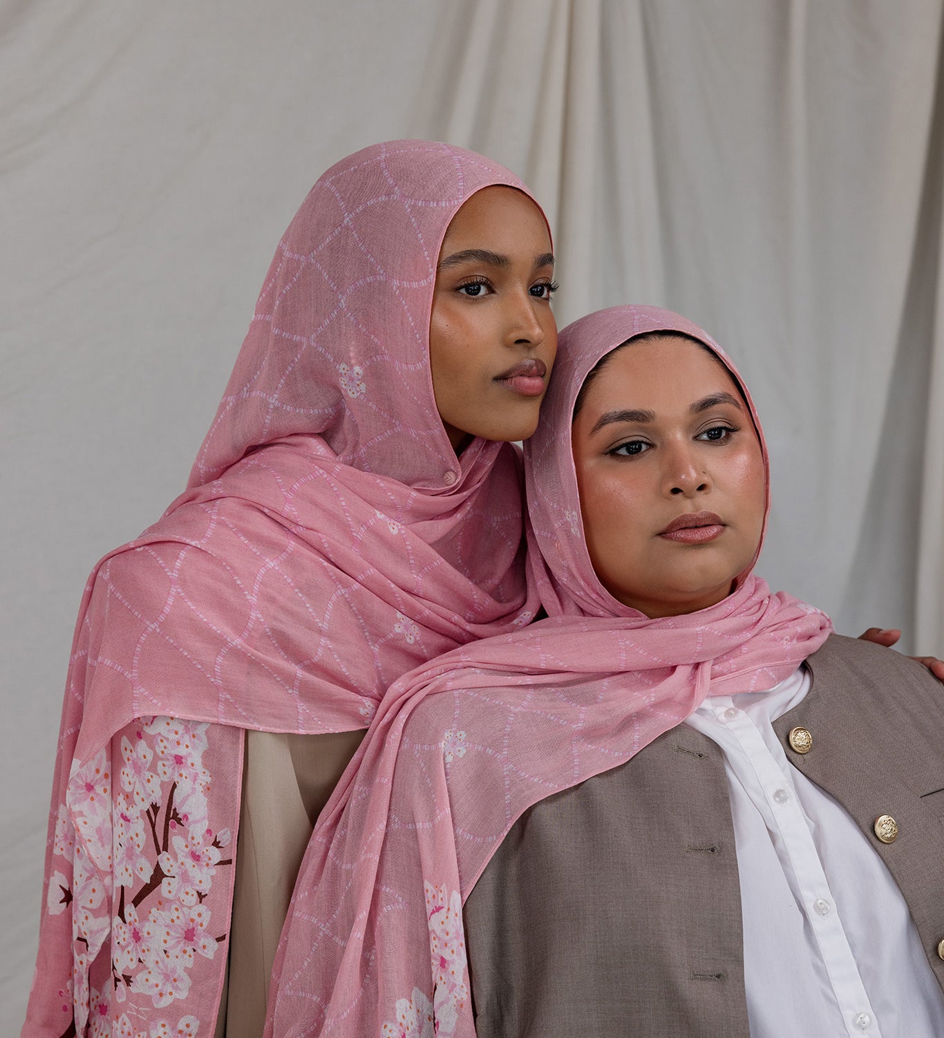 Two models styled in a pink printed hijab featuring cherry blossoms in pink and white.