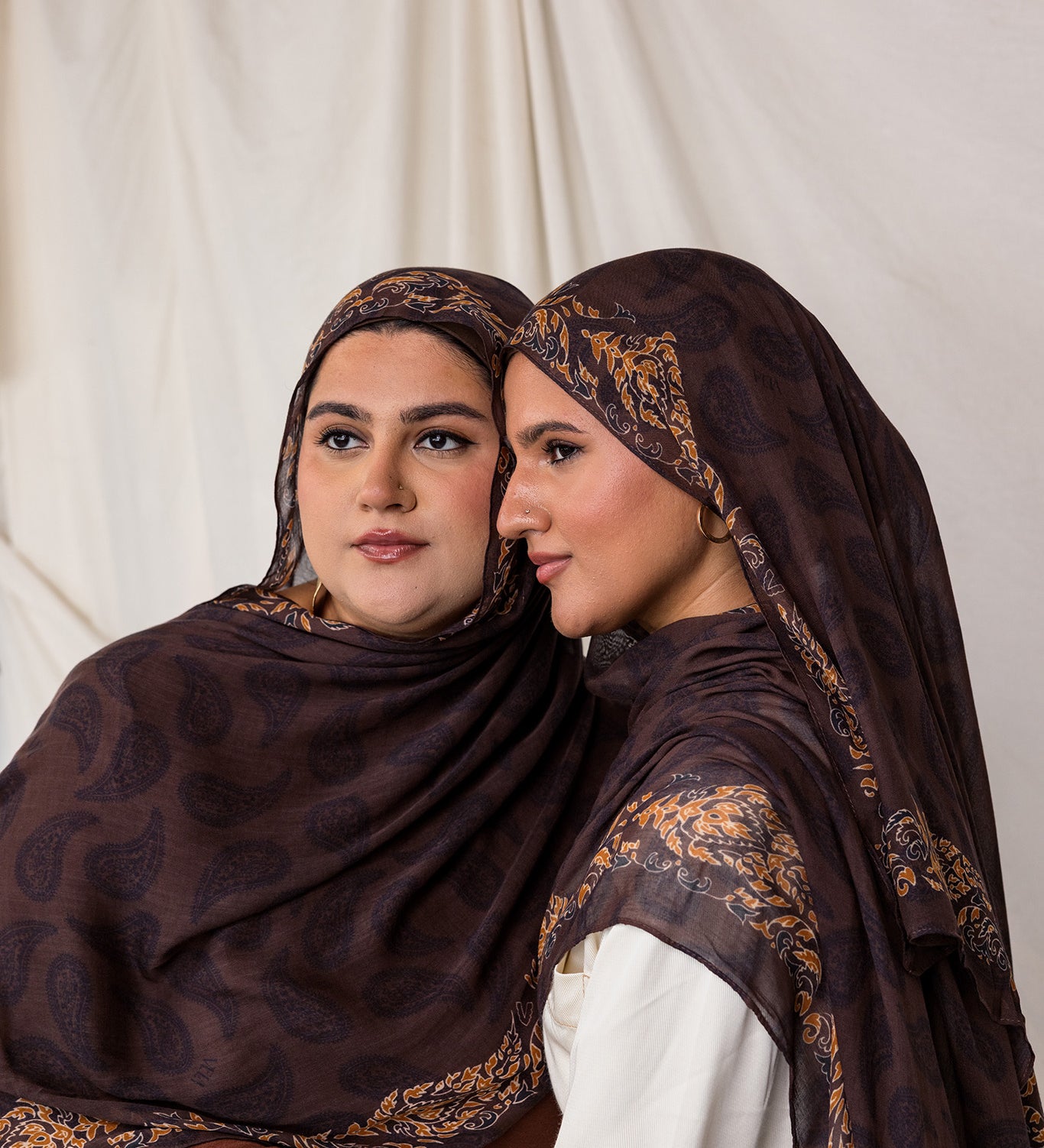 Side profile shot of two women styled in Chocolate Paisley hijabs.