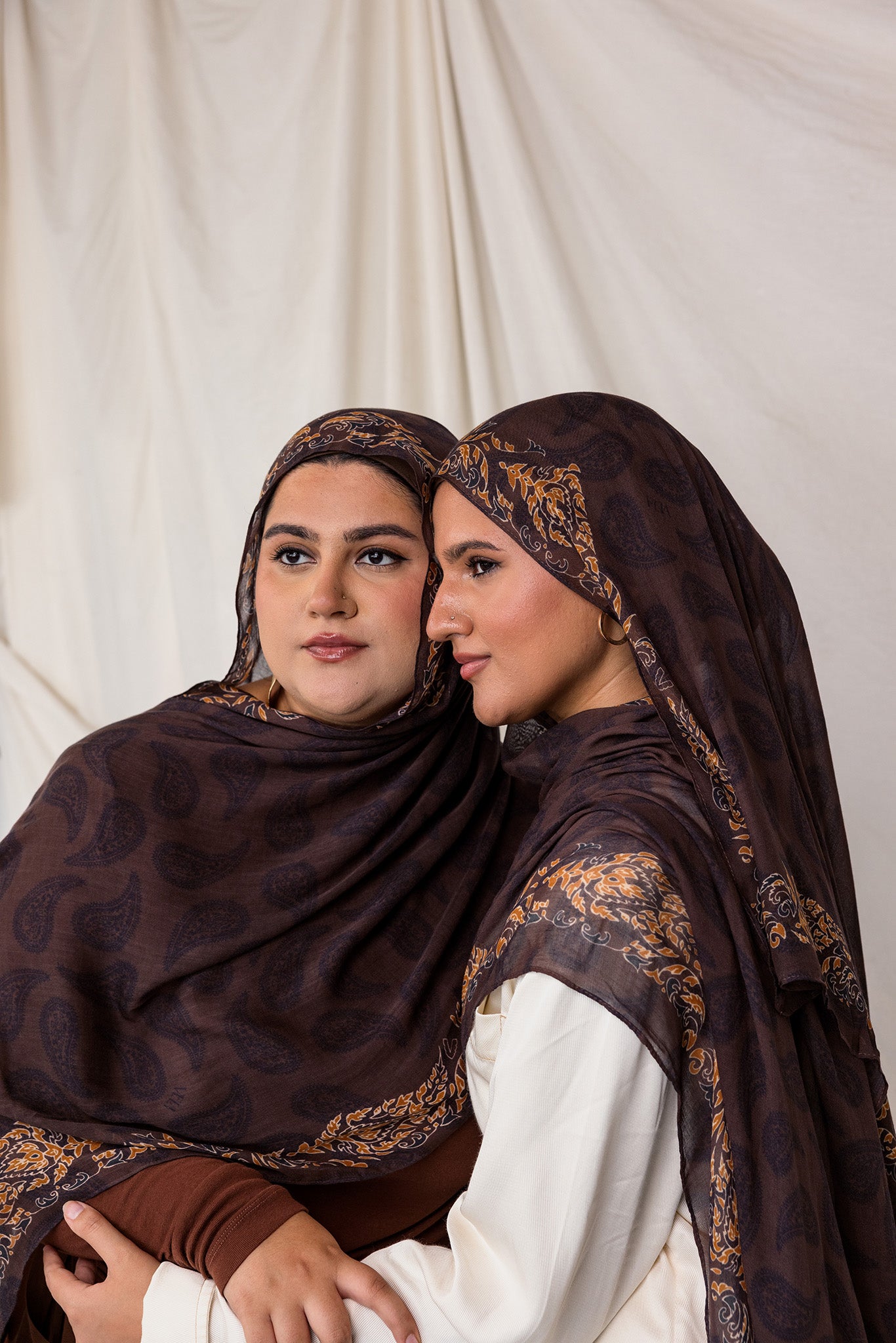 Side profile shot of two women styled in Chocolate Paisley hijabs.