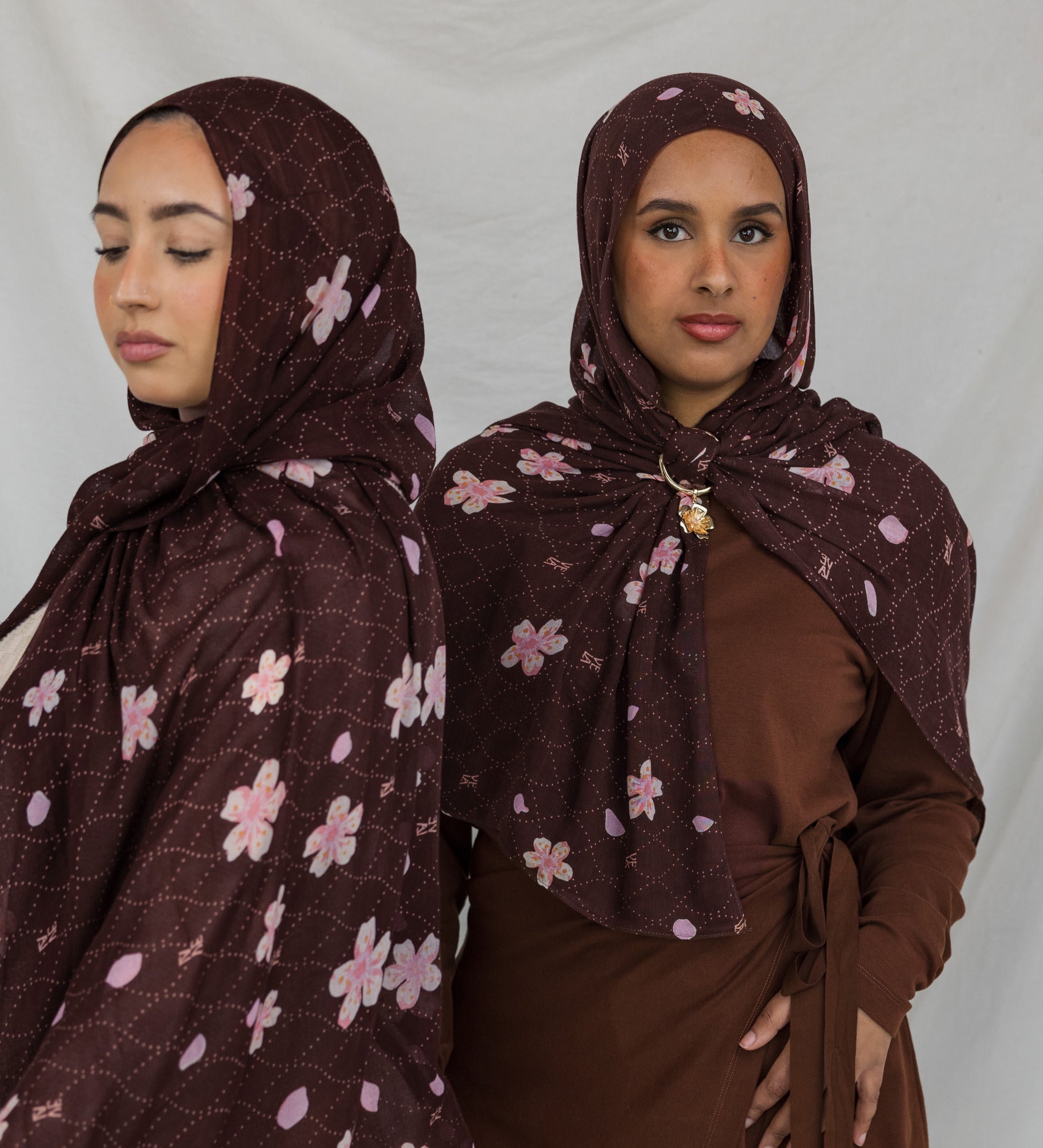 Two models styled in a brown printed hijab with pink and white cherry blossoms.