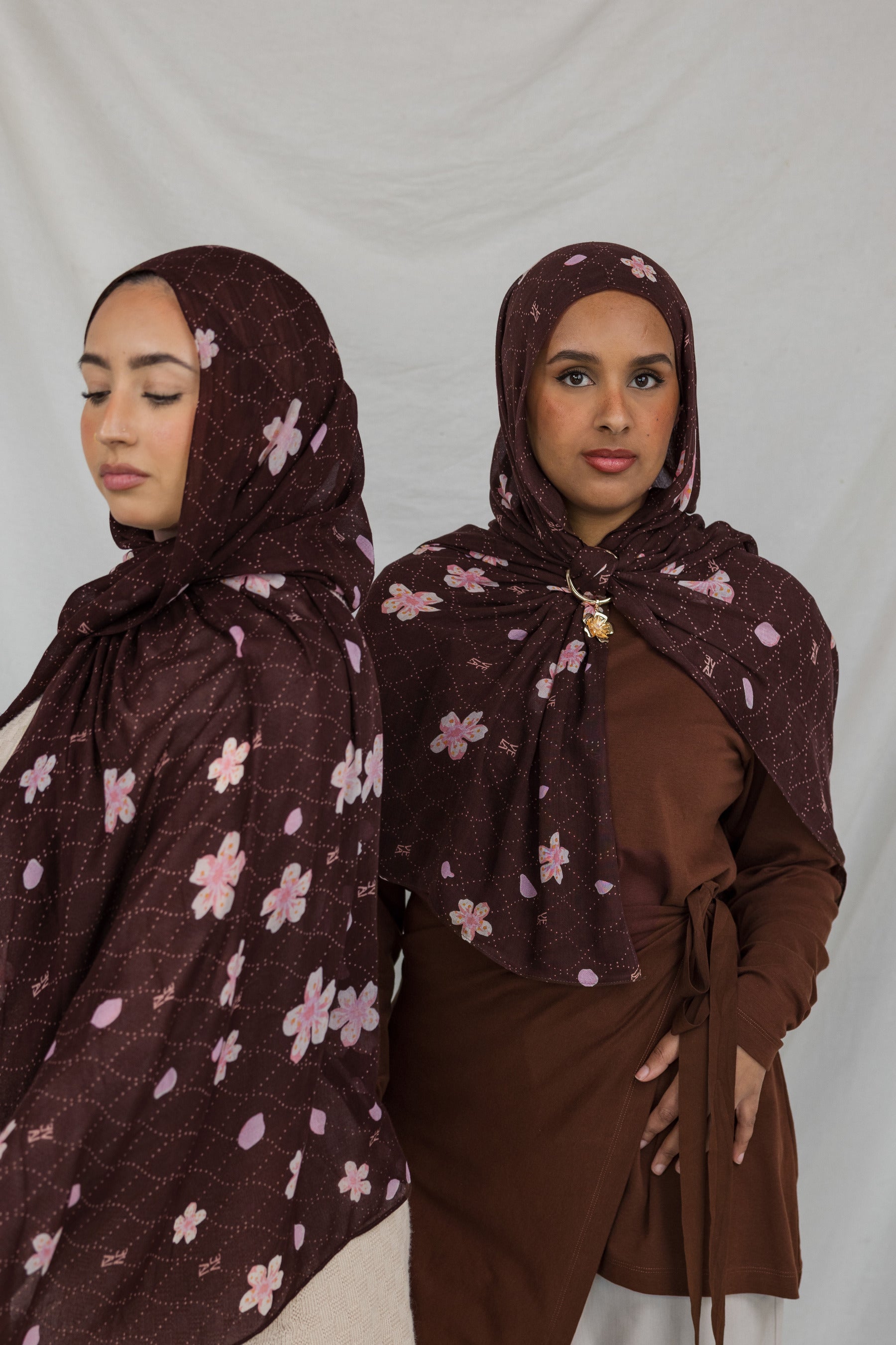 Two models styled in a brown printed hijab with pink and white cherry blossoms.