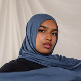 Model wearing a blue hijab against a plain background.
