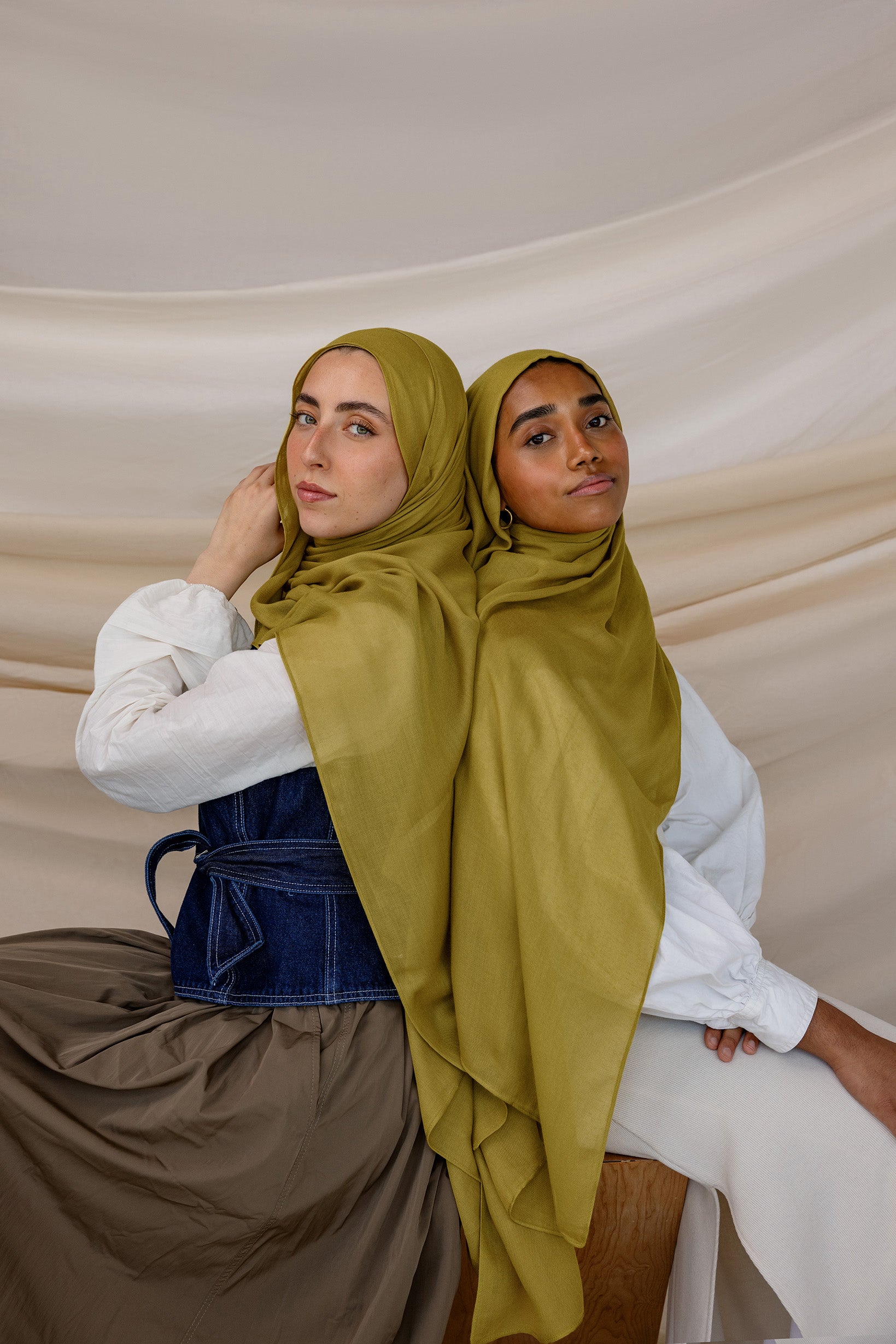 Two models wearing Guava Green hijabs with draping to the side against backdrop.