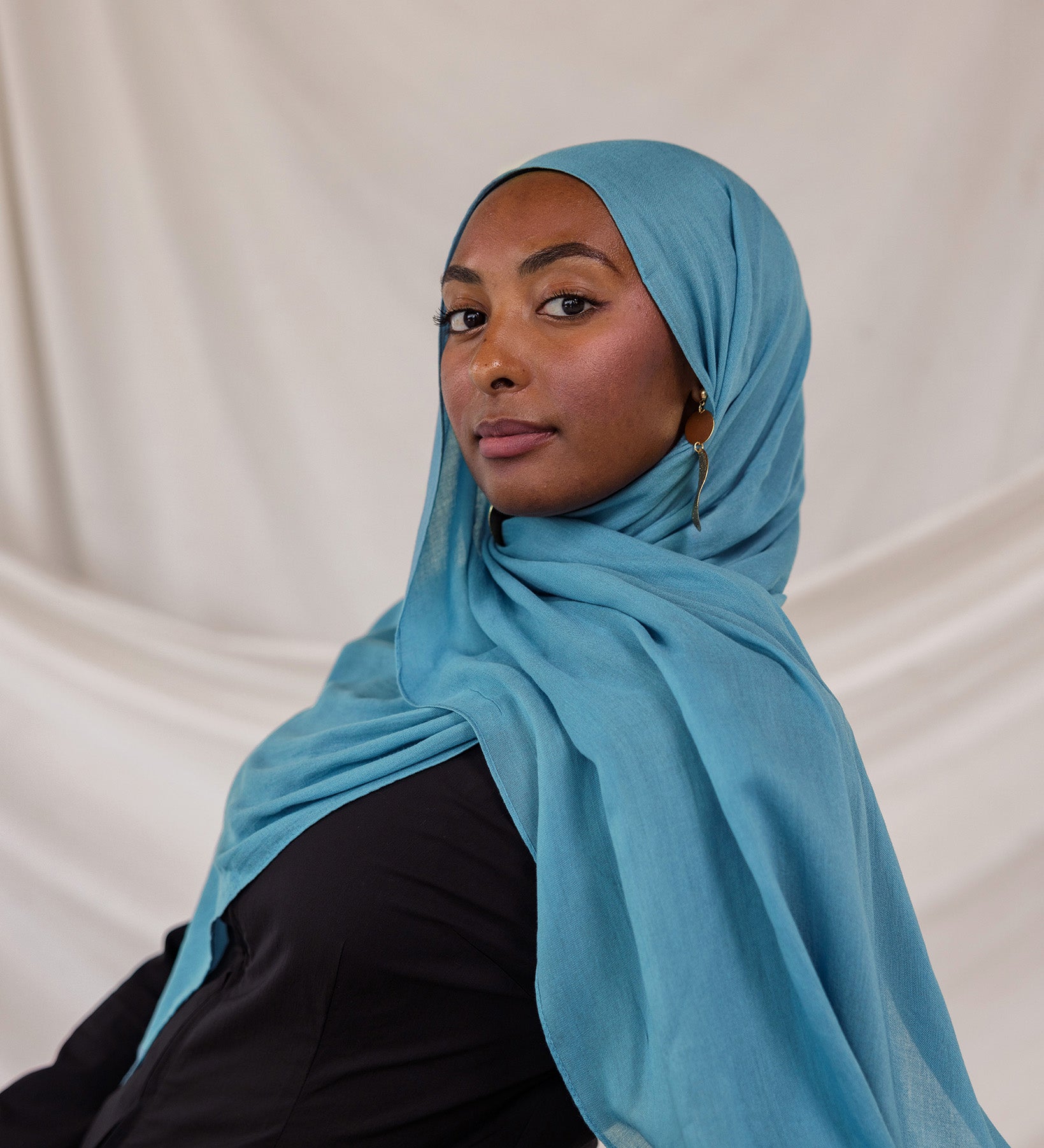 Person wearing a bright blue hijab against a plain background
