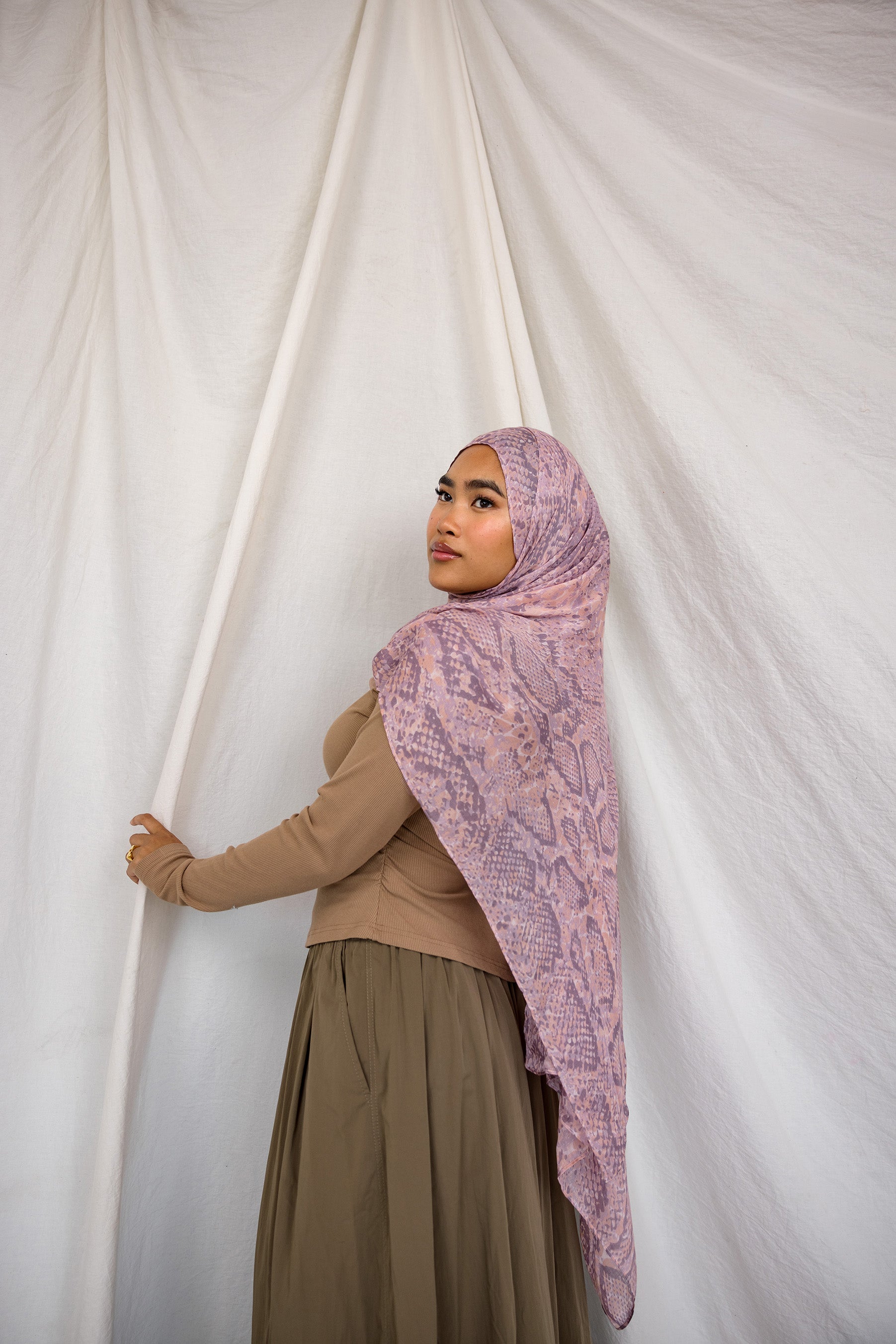 Image of model posing in pink and purple snakeskin scarf showing long draping ability of fabric.