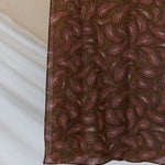 A product image showcasing a brown red toned paisley print hijab.