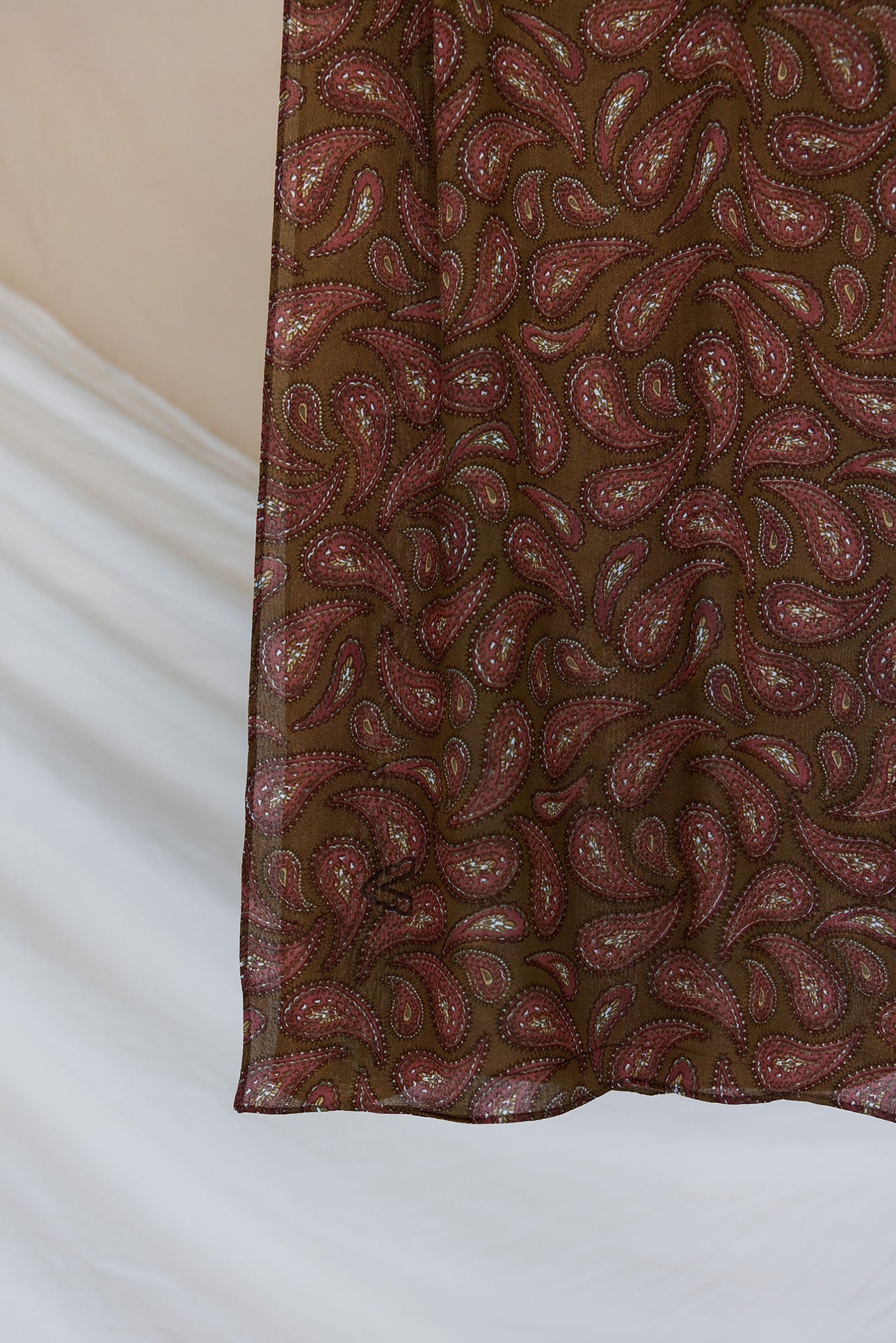 A product image showcasing a brown red toned paisley print hijab.