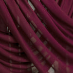 Maroon hijab suspended and gently draped to show the lightweight fabric and texture in soft lighting.