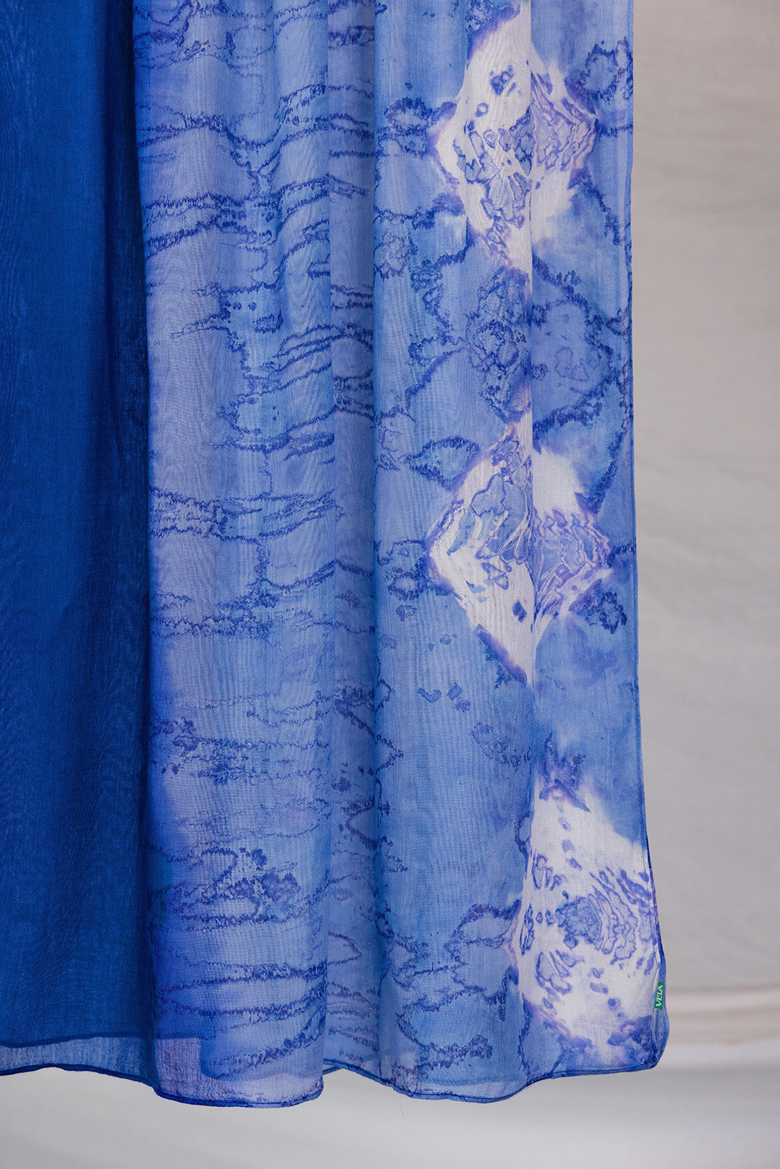 Blue hijab with white abstract shell patterns on a white background
