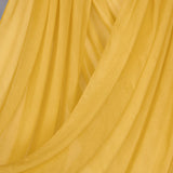 Close-up of bright yellow hijab hanging in front of backdrop