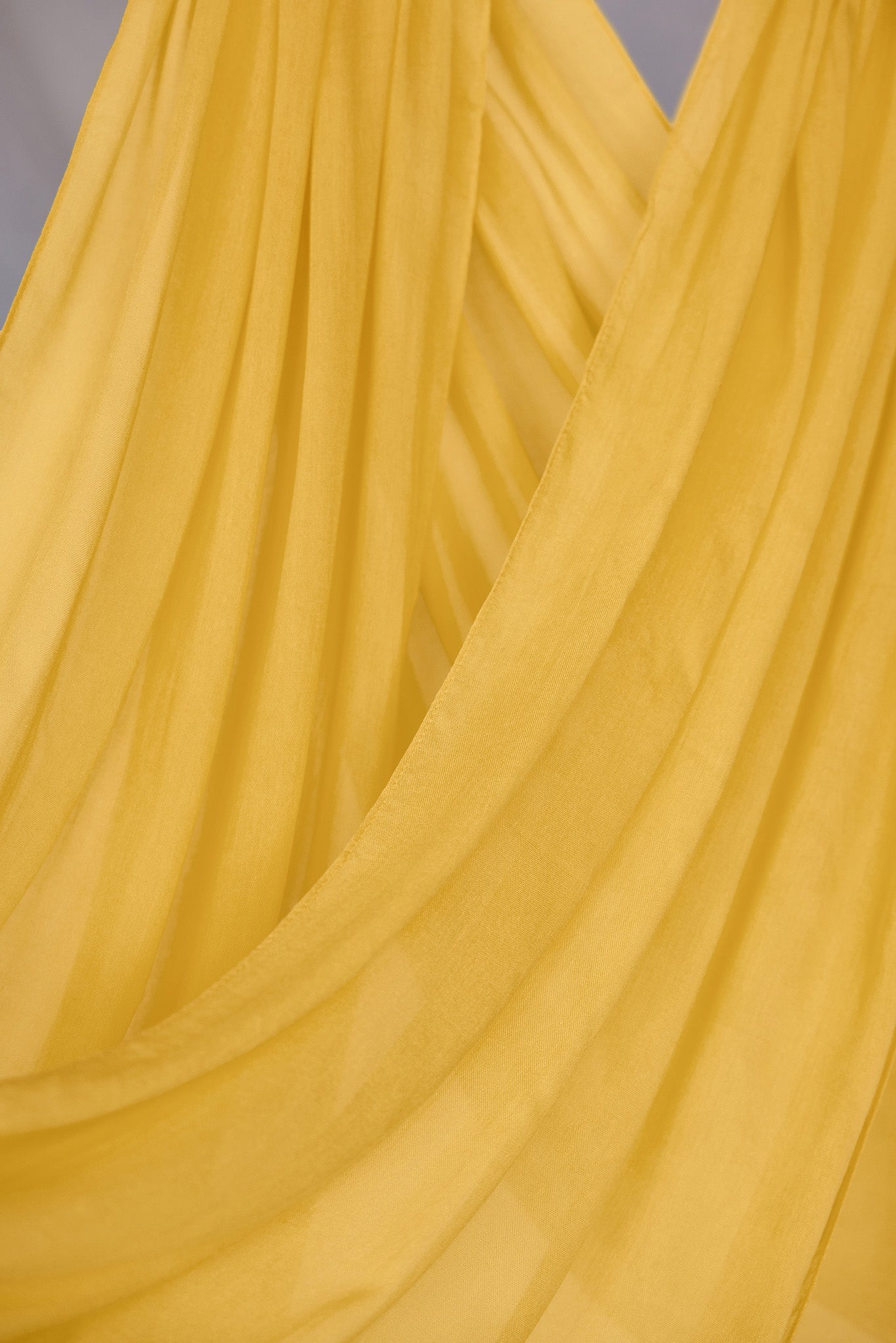 Close-up of bright yellow hijab hanging in front of backdrop