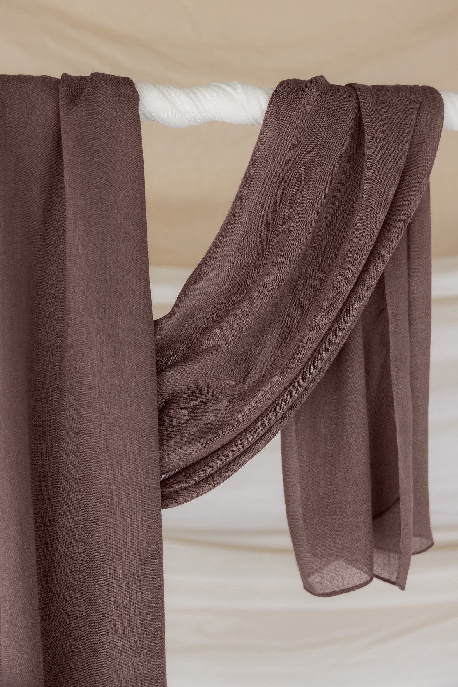 Taupe hijab draped in front of backdrop.