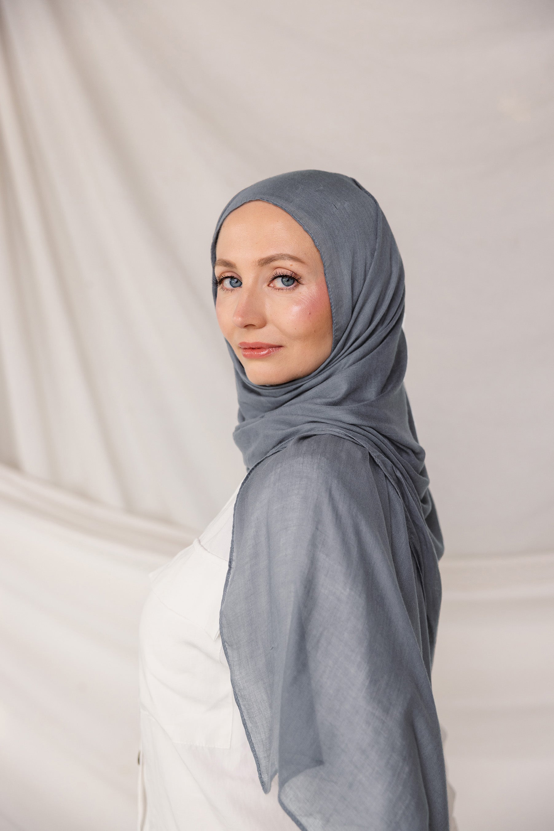 Soft woven hijab in dark sage green, neatly styled on model display its color and lightweight woven texture.