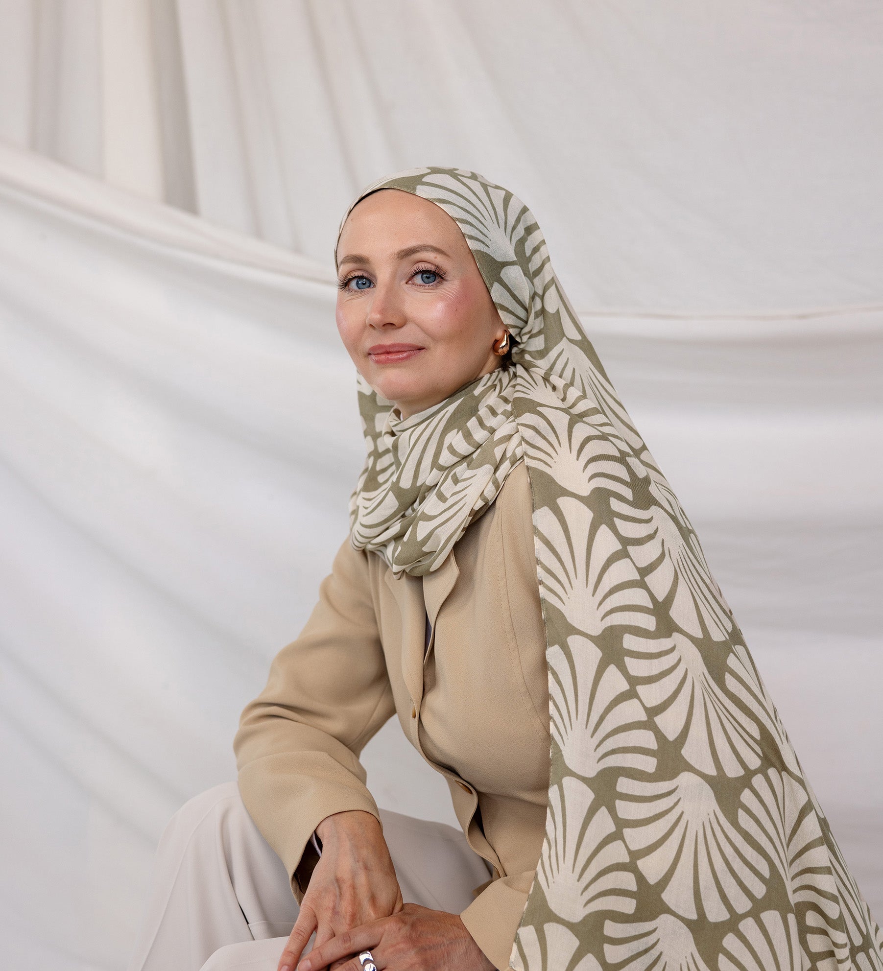 Woman wearing a patterned Sand Shells hijab and beige outfit against a white background