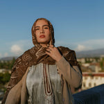 Printed modal hijab with curving Arabic script inspired by themes of home and identity.