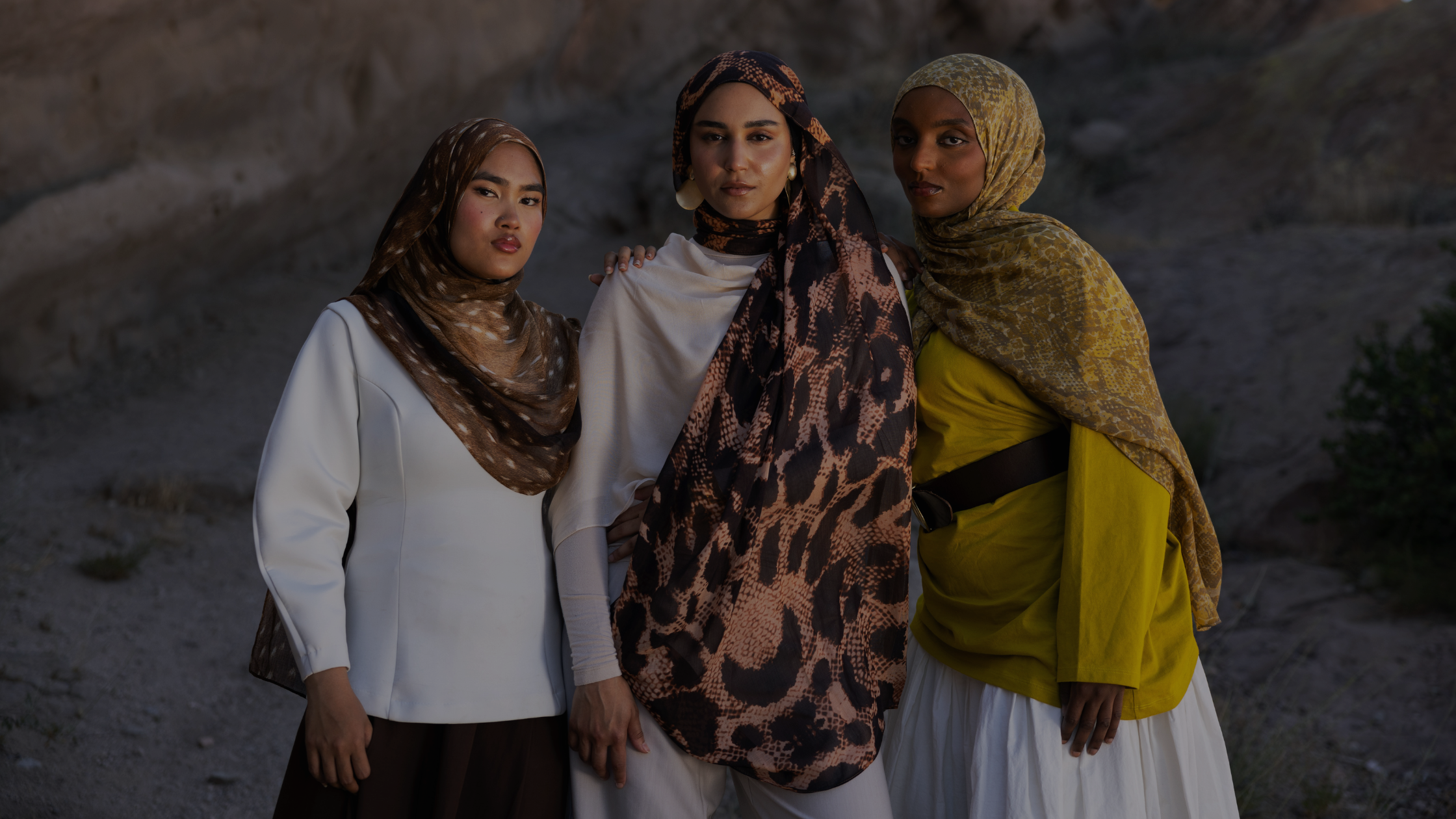 Three girls wearing hijab standing together in printed scarves.