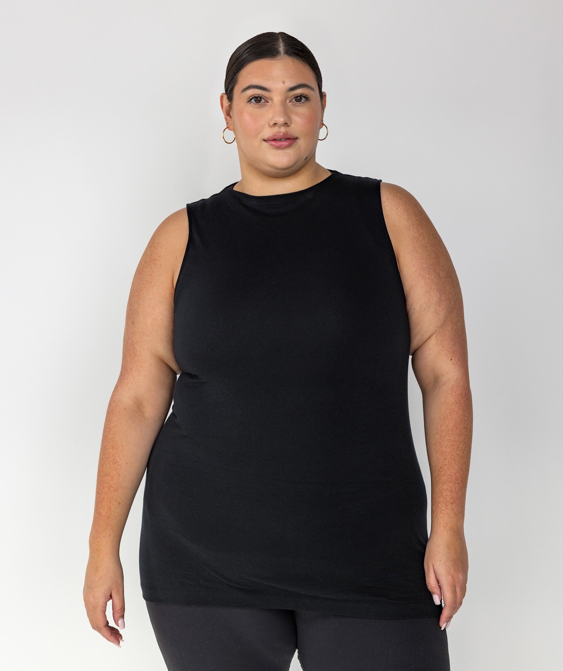 Woman wearing a black sleeveless top and black leggings on a white background