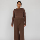 Model styled in a brown outfit with wide-leg pants on a white background