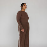 Woman wearing a brown outfit with wide-leg pants on a white background