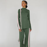 Woman wearing a green outfit with pink stripes on a white background